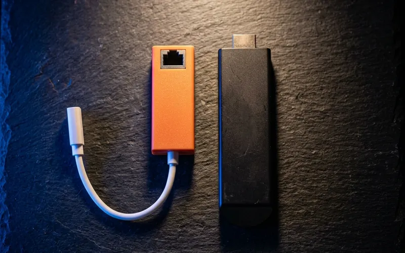 Ethernet adapter dongle with a Firestick device on a slate surface